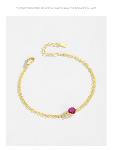 Close-up of S925 silver clasp and faceted red zircon on a gold double-chain bracelet