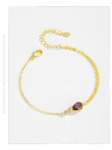 Macro shot of S925 sterling silver stamp and blue-purple teardrop zircon on a gold chain