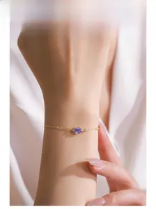 Detailed shot of a gold double-layer silver bracelet featuring an oval purple crystal stone
