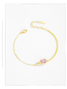 Detail of gold bracelet with rectangular pink gemstone and adjustable lobster clasp