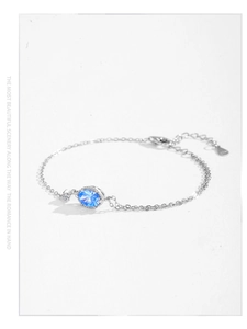 Detail of S925 sterling silver chain featuring an oval blue crystal and tiny zircon accent