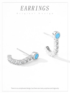 Macro shot of silver semi-hoop earring with turquoise stone and cubic zirconia inlay
