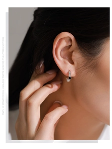 Detailed view of silver twist texture hoop earring with black gemstone on ear