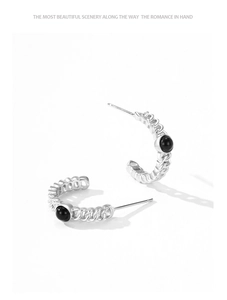 Detailed view of S925 silver C-shape earrings with braided texture and black gemstone