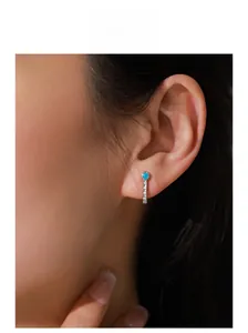 Close-up of S925 silver turquoise stud earrings with micro-paved diamonds on model