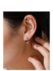 Gros plan de boucles d'oreilles rétro en argent S925 tressé avec zircon noir porté