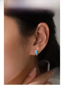 Close-up of S925 sterling silver turquoise stud earring worn by a model in soft lighting