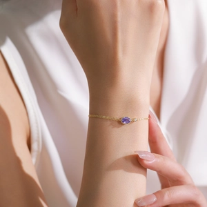 Elegant S925 silver gold chain bracelet featuring an oval purple crystal on female wrist