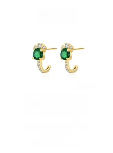 Detail of J-shaped gold earrings with green zircon and pavé white stones in macro view