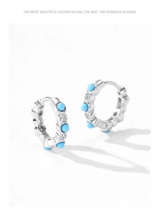 Detail of S925 silver huggie earrings featuring turquoise stones and white zircons