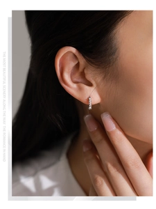 Gros plan de boucles d'oreilles en argent S925 avec zircons verts et blancs sur un mannequin