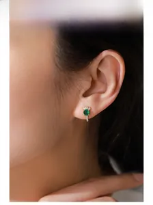 Model wearing gold S925 silver stud earrings with emerald zircon and white diamonds