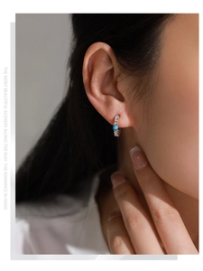 Détail d'une boucle d'oreille en argent S925 avec pierre bleue et texture tressée