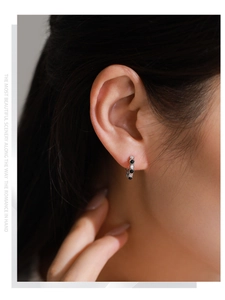 Détail des boucles d'oreilles huggie en argent S925 avec zircons noirs et blancs sur modèle