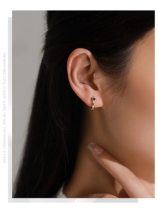 Close-up of S925 silver turquoise stud earring with green and white gems on model