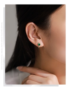 Macro detail of S925 silver J-shaped earrings with green gemstone and small diamonds