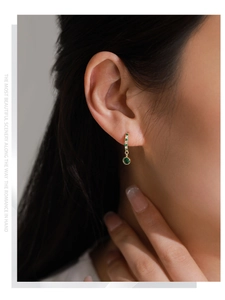 Close-up of vintage S925 silver gold-plated earrings with emerald green pendant