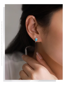 Close-up of S925 silver stud earring with emerald green zircon on a female model