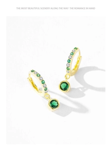 Detailed macro view of S925 silver gold-plated earrings featuring green stone and zircons