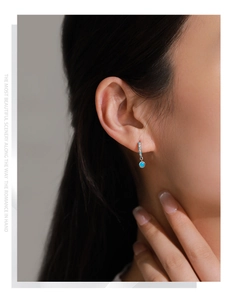 Close-up of elegant S925 silver hoop earrings with emerald zircons worn by a model
