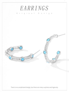 Detail of silver C-hoop earrings with turquoise and zircon stones in a micro-pave setting