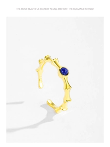 Detail view of a gold bamboo-style silver ring featuring a round blue lapis stone inlay