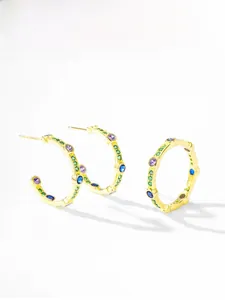 Macro detail of gold C-shaped earrings with green pave and colorful zircon stones