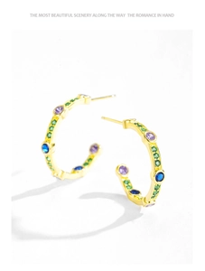 Detailed shot of C-shaped gold-plated silver earrings with vibrant colored gemstones