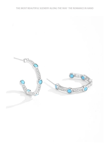 Macro detail of 925 silver turquoise C-shaped stud earrings with micro-set cubic zirconia