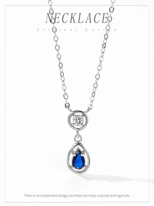 Macro shot of silver drop necklace featuring blue pear-cut gemstone and white zircon