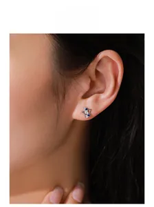 Close-up of 925 sterling silver star stud earring with blue stones on model's ear