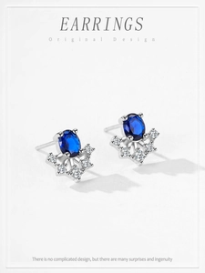 Detailed macro view of S925 silver stud earrings with oval blue sapphire and zircons