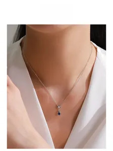Close-up of teardrop blue gemstone pendant on a silver necklace worn by a model