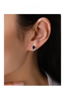 Close-up of vintage S925 silver sapphire stud earrings worn on a model's ear