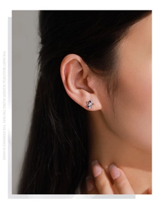 Close-up of 925 sterling silver star stud earring with blue zircon on model ear