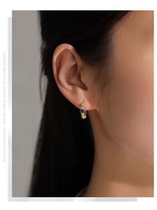 Gros plan d'une boucle d'oreille créole bambou en argent S925 dorée avec lapis-lazuli