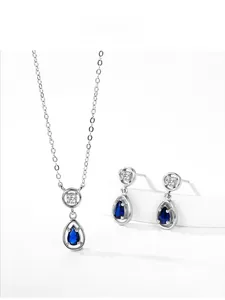 Macro detail of 925 silver necklace and earrings set with blue teardrop zircon