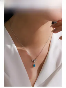Model wearing 925 silver necklace featuring star-shaped charms and a blue oval gemstone
