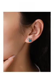 Détail de boucles d'oreilles soleil et étoile en argent avec zircon bleu ovale