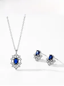 Detail of sapphire blue gemstone pendant and earrings set with sparkling zircon halo