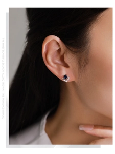 Close-up of elegant S925 silver sapphire stud earrings in a floral snowflake design