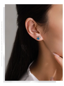 Vue détaillée de boucles d'oreilles soleil et étoile en argent avec zircone bleue sur modèle