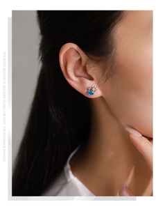 Detailed view of sea-blue oval gemstone stud earrings with silver star accent on model