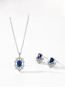 Detail view of 925 silver necklace and earrings set with sapphire and crystal halo