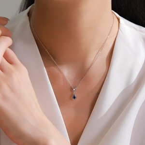 Elegant S925 sterling silver necklace with a blue teardrop pendant on a model wearing white