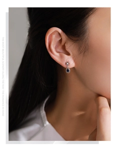 Close-up of S925 silver teardrop earrings with deep blue sapphire on model ear