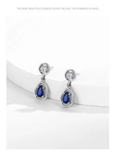 Detailed macro of S925 silver pear-shaped drop earrings with deep blue sapphire gemstone