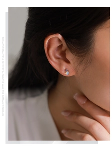 Gros plan de boucles d'oreilles S925 avec zircon violet et opale irisée sur l'oreille