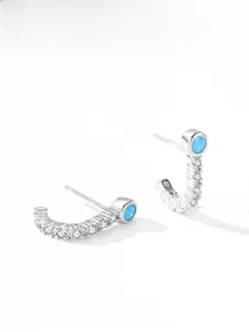Vue macro de boucles d'oreilles C en argent avec zircons et pierre turquoise bleue