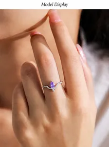Primo piano di un anello in argento a V con gemma viola a goccia sulla mano di donna